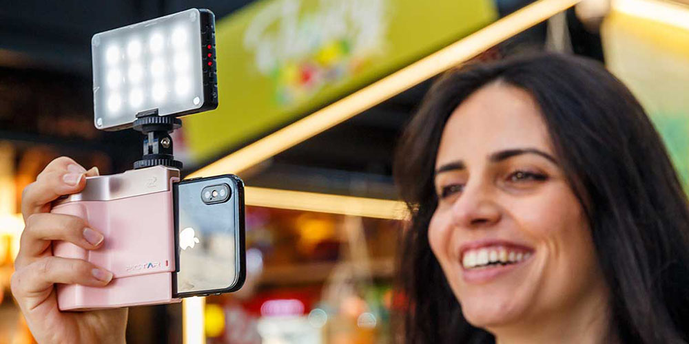 A person taking a photo on their phone using a light attachment