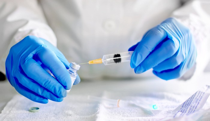 A syringe being filled with a vaccine from a vial.