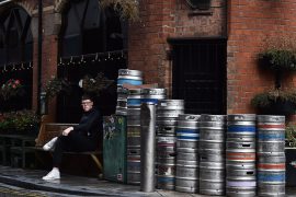 A customer is seen sitting outside Bittles bar beside beer kegs in Belfast city centre on October 14, 2020 in Belfast, Northern Ireland.