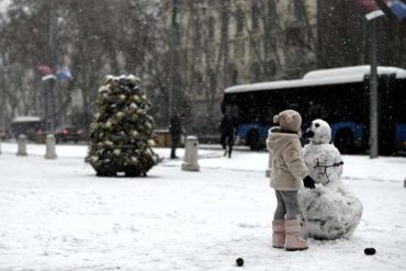 Ein Mädchen baut auf einer Straße in Madrid einen Schneemann. Foto: Óscar Cañas/EUROPA PRESS/dpa