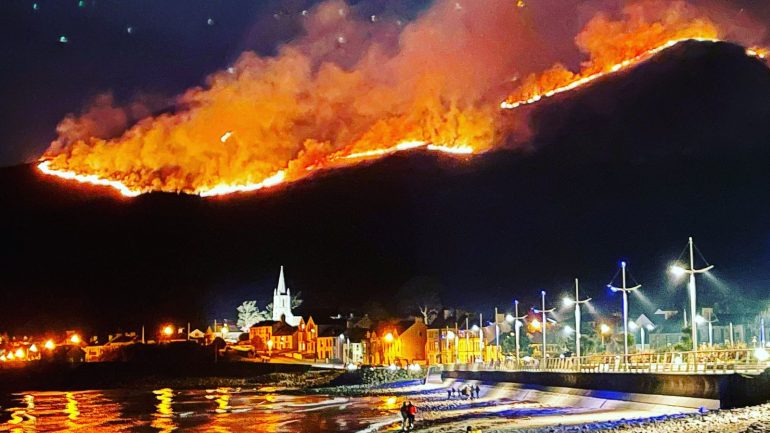 Uma enorme fogueira de tojo atravessa as Montanhas Mourne em Co Down, vista de Newcastle