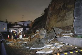 Menschen stehen vor eingestürzten Teilen einer Klippe. Eine Tsunami-Warnung in Folge eines starken Erdbebens im Nordosten Japans ist wieder aufgehoben worden. Foto: ---/Kyodo/dpa
