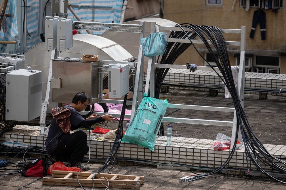 epa09406967 A worker lays cables to install 5G antennas on the roof of Hong Kong, 09 August 2021. Four existing mobile network operators in Hong Kong have launched commercial 5G services since April 2020.  EPA / JEROME FAVRE